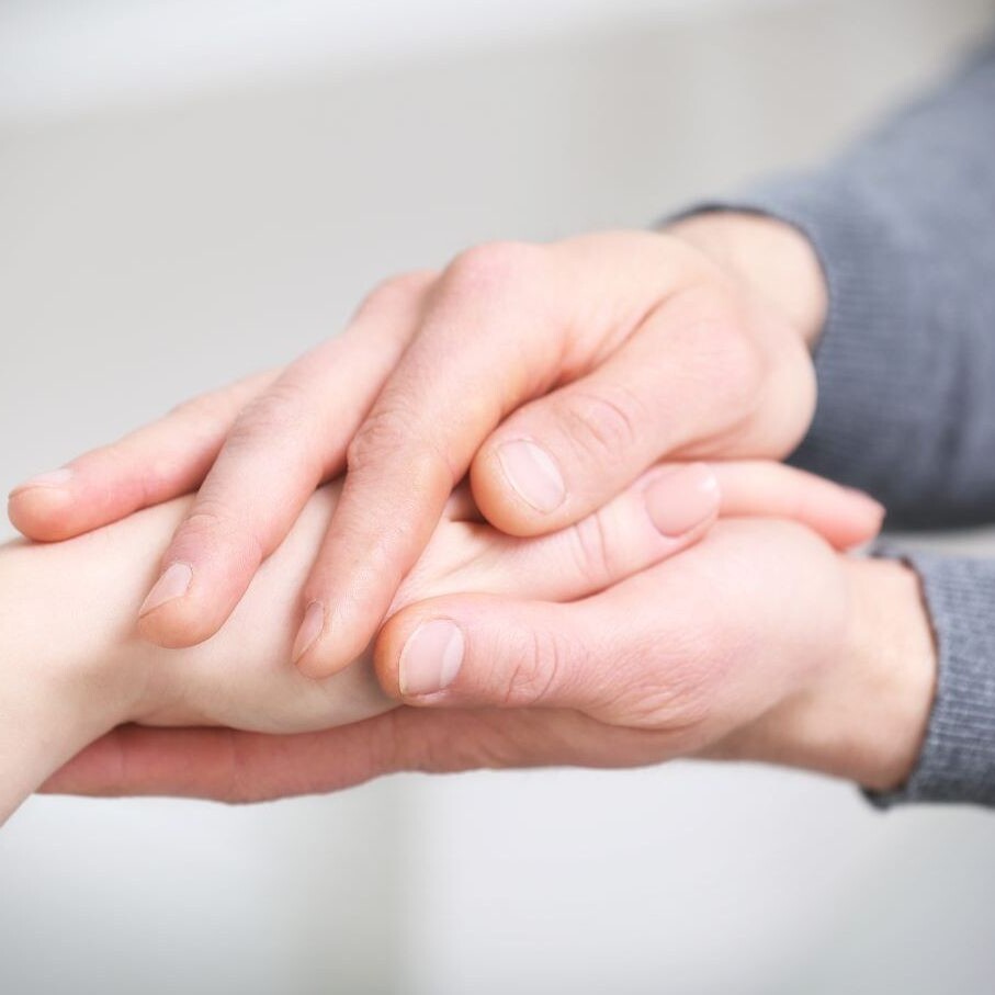 Close up of a man's hands holding a woman's hands.