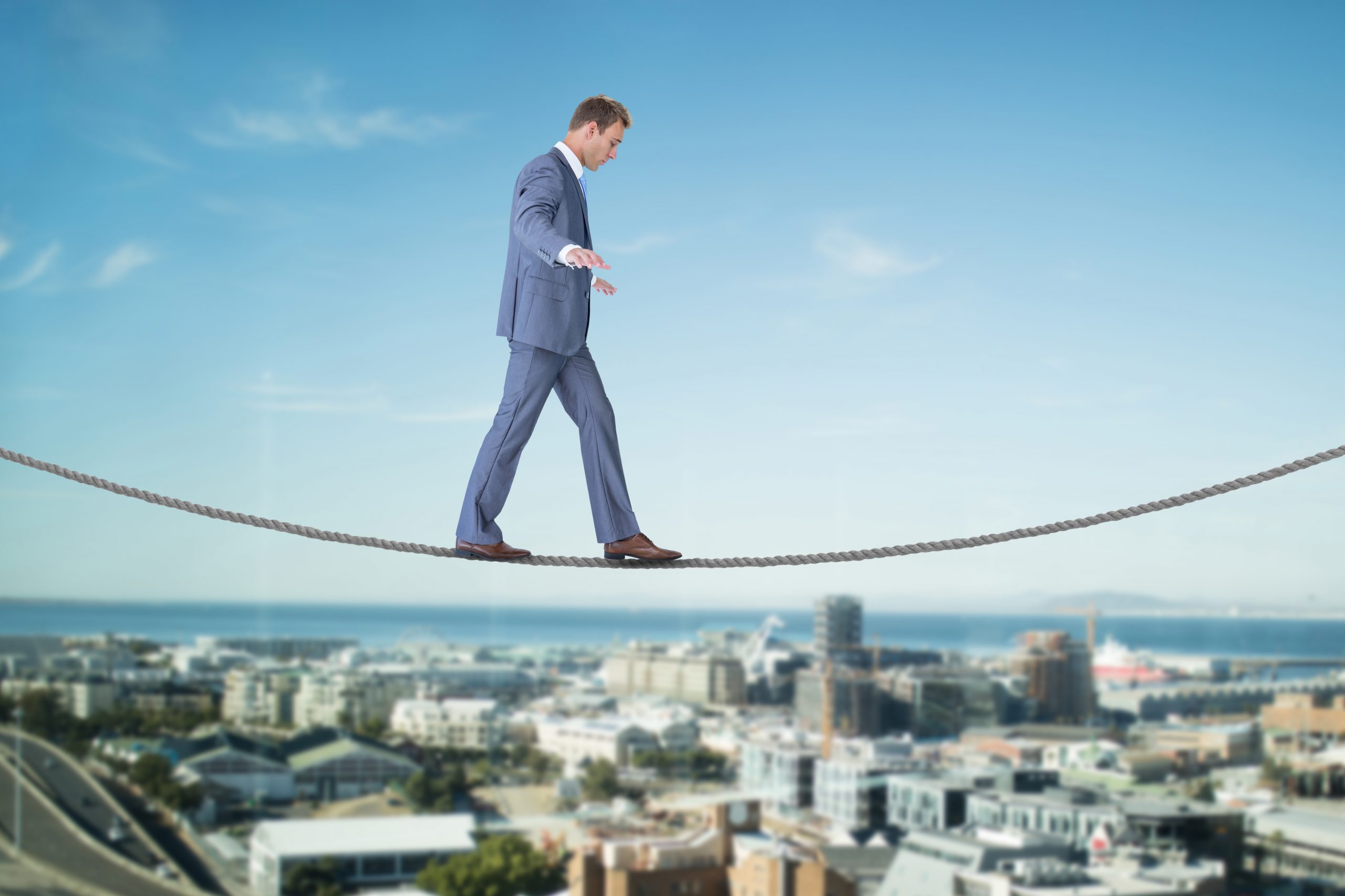 Businessman walking a tightrope over a city.