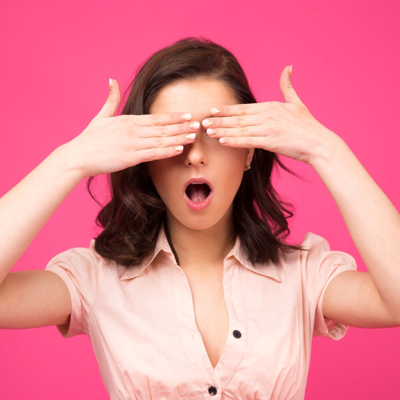 Woman covering her eyes with hands against pink background