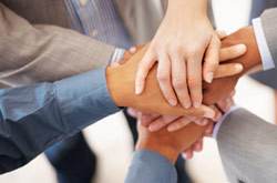 Image of team stacking their hands as part of a group huddle